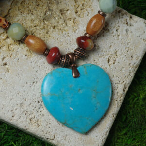 A big, blue stone heart is the focal piece of a beaded gemstone necklace.