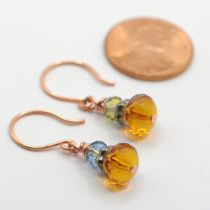 Earrings made with copper wire and blue and amber glass beads.