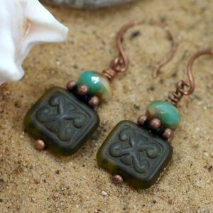 Earrings made from beads decorated with a ram's horn symbol.